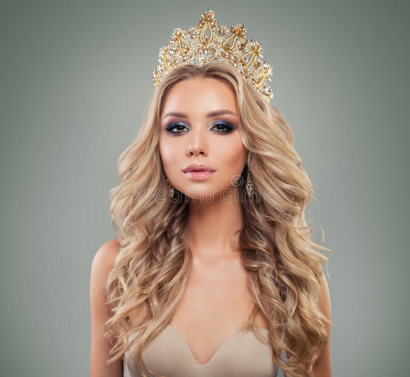 Ξανθή γυναίκα με το makeup, μακροχρόνιο σγουρό hairstyle, χρυσή κορώνα κοσμήματος, πορτρέτο μόδας στοκ φωτογραφία
